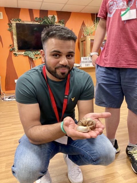 A male volunteer in our young carers&#39; project holds a snail on a trip to Chessington World of Adventures