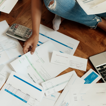 Lots of bills and invoices on the floor with a calculator