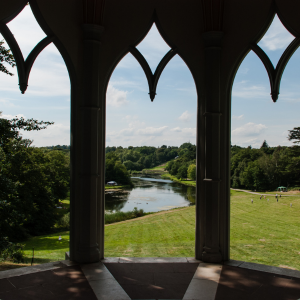 A view of Painshill Park picture through big open windows of a stone built structure.