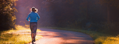 A runner, running in the late autumn sun towards trees