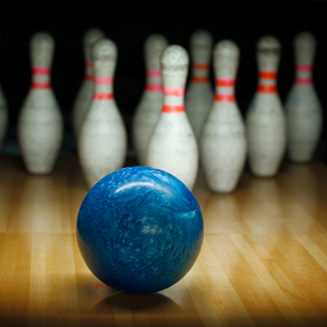 Blue bowling ball heading towards bowling pins