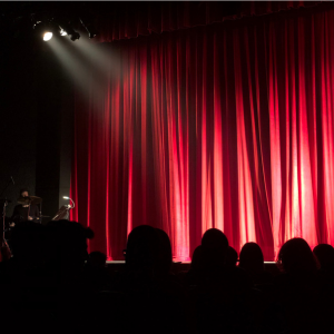 An empty stage with red curtains and a spotlight shining
