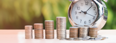 Stacks of coins in front of a clock.