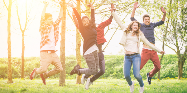 Young adult carers jumping in a sunny field