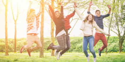 Young adult carers jumping in a sunny field